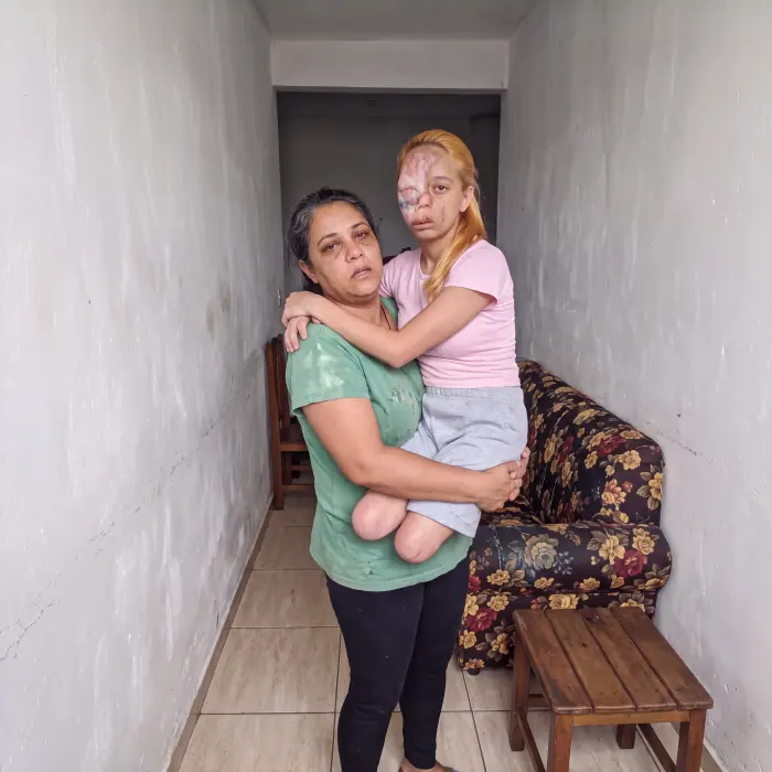 Juliana no colo da mãe, no corredor de casa